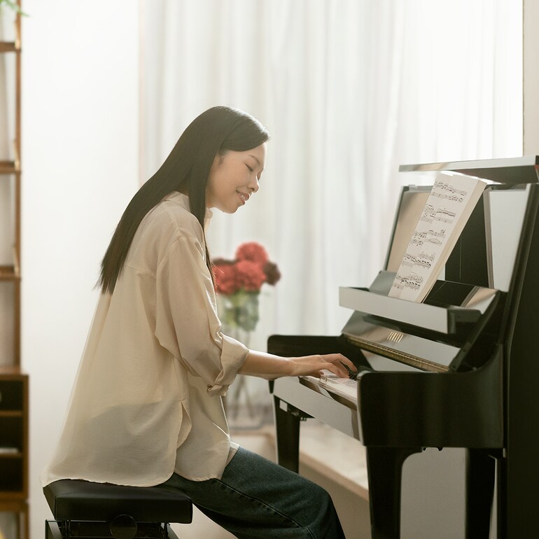一位女士享受彈奏 B 系列直立式鋼琴