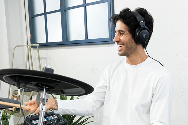 A man smiling while playing electronic drum kit