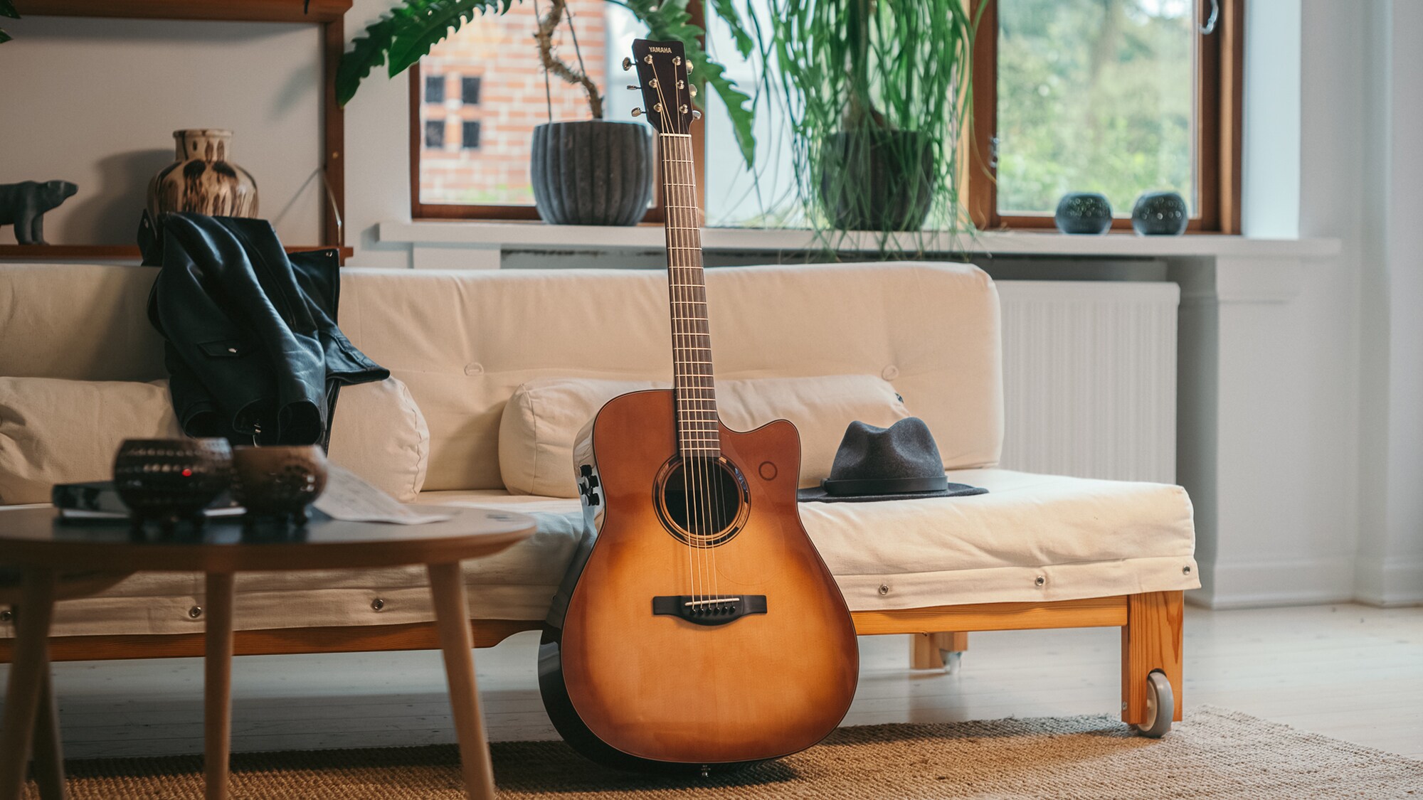 TAG3 C acoustic guitar placed on a sofa with a bag beside it.