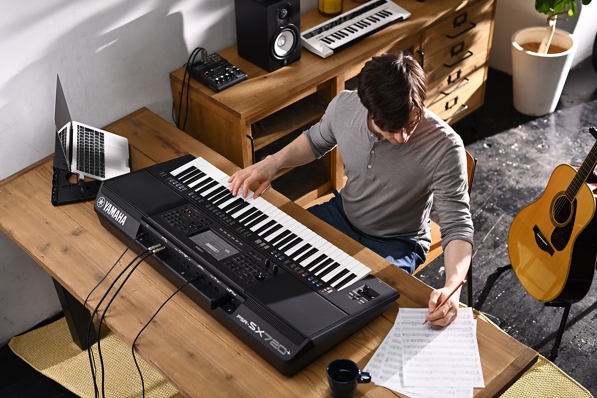 演奏者一邊演奏 Yamaha 數位工作站 PSR-SX720+ 一邊在樂譜上書寫的照片