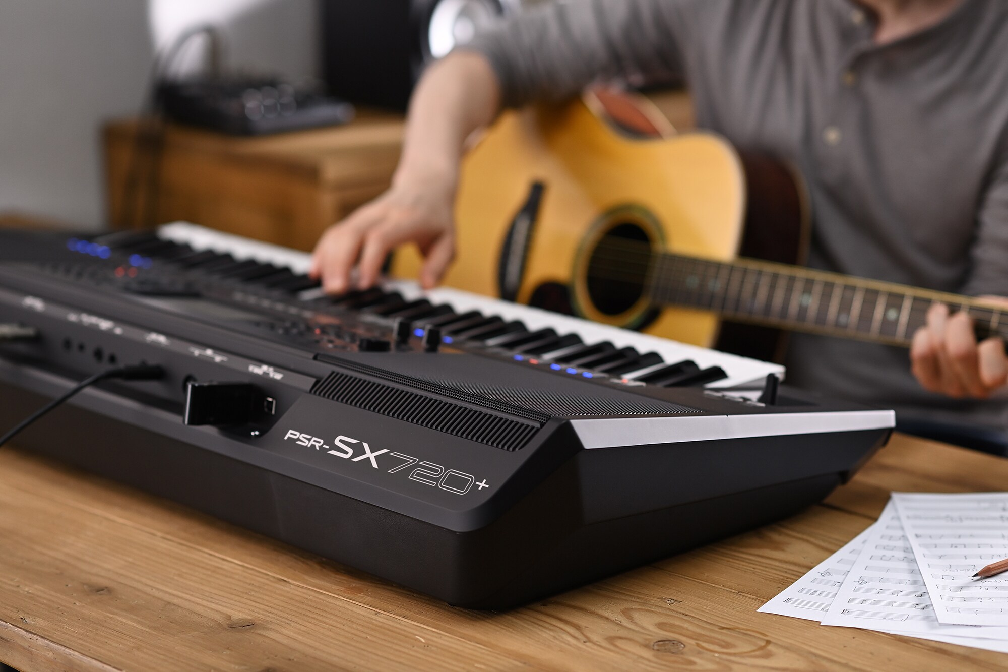 演奏者一邊抱著吉他一邊演奏 Yamaha 數位工作站 PSR-SX720+ 的照片