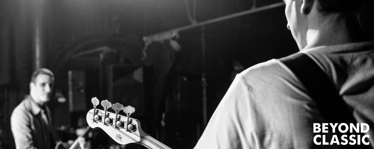 Beyond Classic. Looking over the shoulder of a bassist with BB who is looking at another musician.