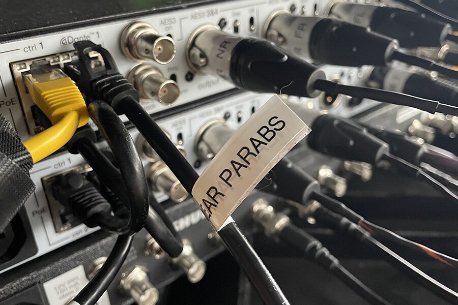 Close-up of audio equipment connections showing Dante network cables and parabolic microphone outputs