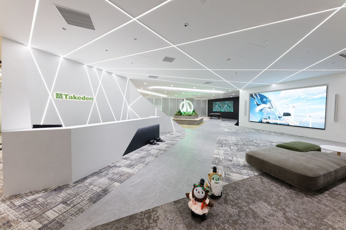 TAKEDEN JP Tower Osaka 辦公室的現代化入口空間，配有線性天花板照明、大型數位顯示器和休息區座位