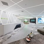 Image: Modern entrance space at TAKEDEN JP Tower Osaka office with linear ceiling lighting, large digital displays, and lounge seating